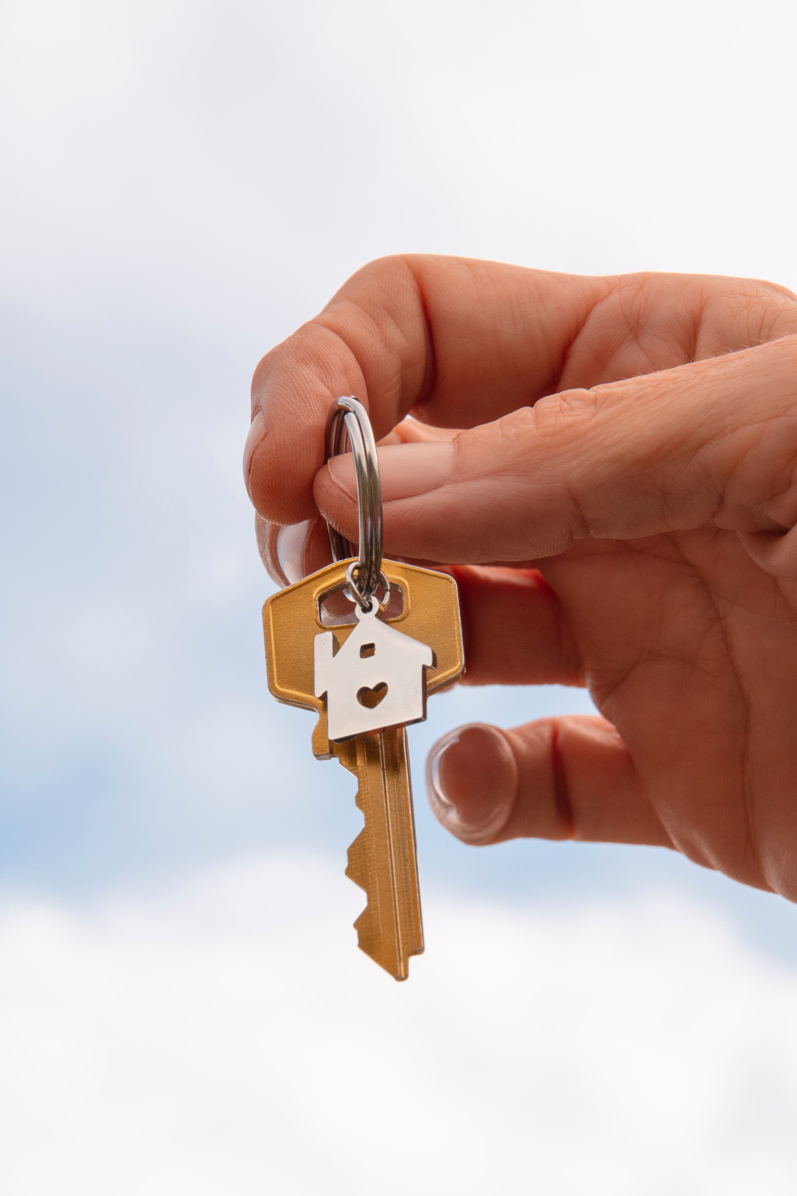Una mano sosteniendo la llave de una casa con un llavero con forma de hogar